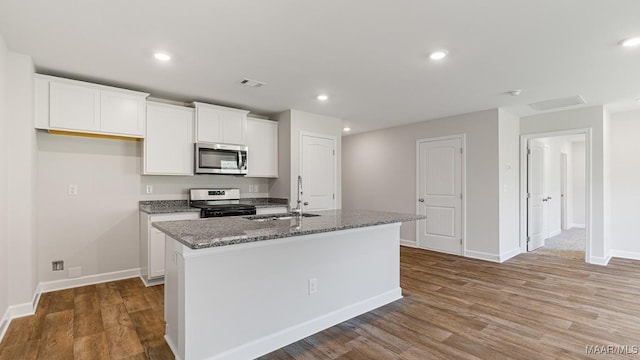 6004 Cunningham Trl, Montgomery, AL 36116 - kitchen featuring appliances with stainless steel finishes, a sink, a center island with sink, white cabinetry, and wood finished floors