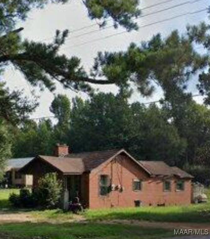 view of side of home with a lawn and a chimney