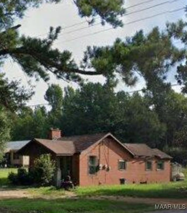 view of side of home with a lawn and a chimney