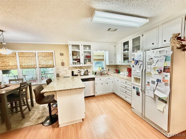 36 Wilkins Rd, Selma, AL 36701 - kitchen featuring white refrigerator with ice dispenser, a peninsula, stainless steel dishwasher, a textured ceiling, and light wood-type flooring