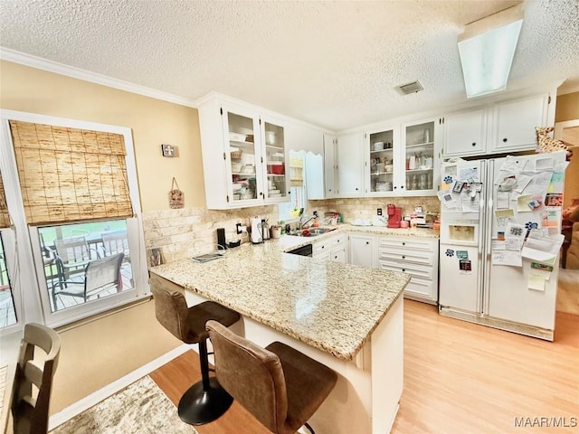 36 Wilkins Rd, Selma, AL 36701 - kitchen featuring white refrigerator with ice dispenser, a textured ceiling, a sink, light wood-style flooring, and a peninsula