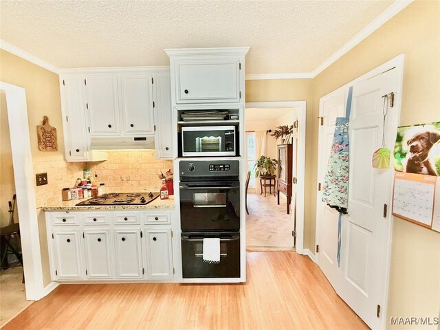 36 Wilkins Rd, Selma, AL 36701 - kitchen with black appliances, light wood-style flooring, under cabinet range hood, white cabinets, and crown molding