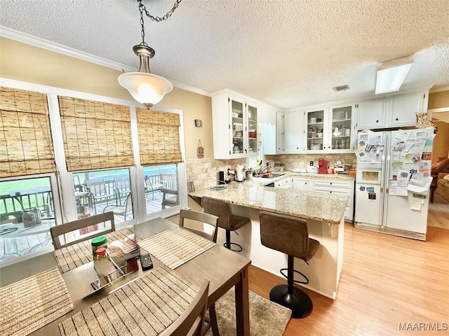 36 Wilkins Rd, Selma, AL 36701 - kitchen with white refrigerator with ice dispenser, a peninsula, light wood-type flooring, a sink, and glass insert cabinets