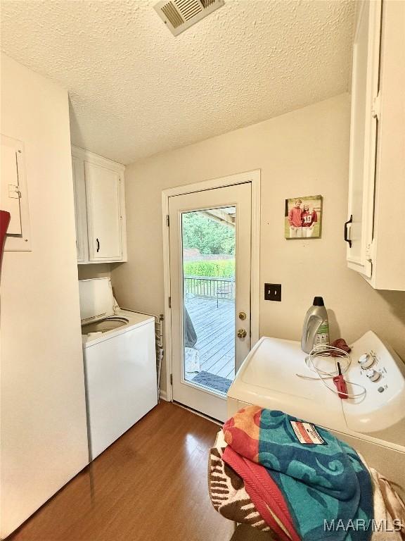 36 Wilkins Rd, Selma, AL 36701 - washroom featuring cabinet space, dark wood-style flooring, a textured ceiling, and washing machine and dryer