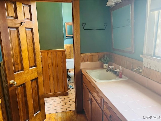 501 Tremont St, Selma, AL 36701 - bathroom with wainscoting, toilet, vanity, wooden walls, and wood finished floors
