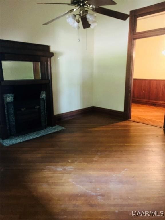 501 Tremont St, Selma, AL 36701 - unfurnished living room featuring wood finished floors, baseboards, a fireplace, a ceiling fan, and wooden walls