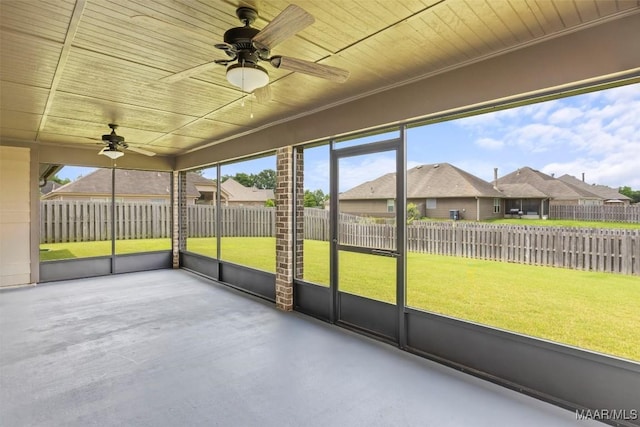 unfurnished sunroom featuring ceiling fan and a residential view