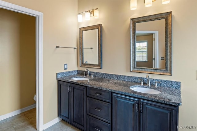 full bath featuring toilet, double vanity, tile patterned flooring, and baseboards
