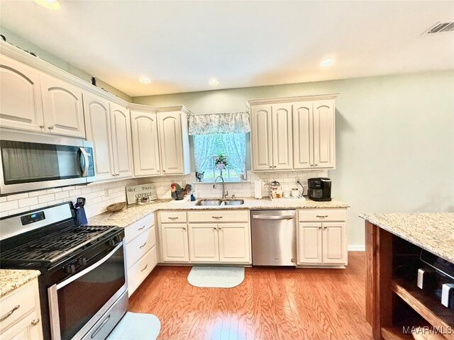 828 Warrior Dr, Valley Grande, AL 36701 - kitchen with stainless steel appliances, a sink, light wood-style flooring, backsplash, and light stone counters