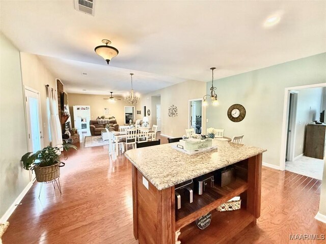 828 Warrior Dr, Valley Grande, AL 36701 - kitchen with wood finished floors, a center island, decorative light fixtures, and light stone countertops