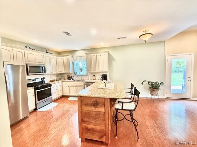 828 Warrior Dr, Valley Grande, AL 36701 - kitchen featuring appliances with stainless steel finishes, light wood-style floors, a breakfast bar area, backsplash, and a sink