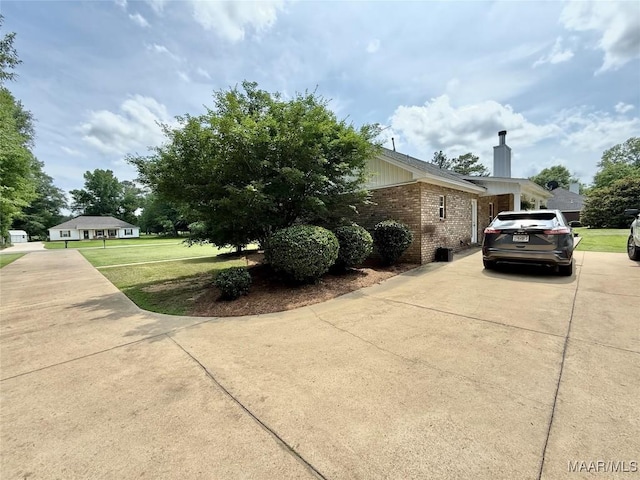 828 Warrior Dr, Valley Grande, AL 36701 - view of side of property featuring brick siding, concrete driveway, a yard, and a chimney