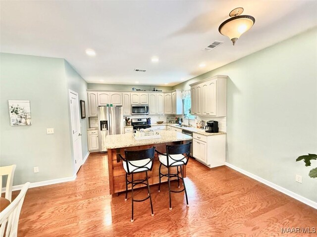 828 Warrior Dr, Valley Grande, AL 36701 - kitchen with stainless steel appliances, light wood-style flooring, a kitchen breakfast bar, light stone countertops, and recessed lighting
