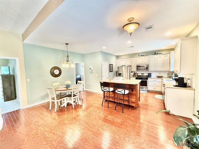 828 Warrior Dr, Valley Grande, AL 36701 - kitchen with appliances with stainless steel finishes, light wood finished floors, a breakfast bar area, a center island, and baseboards
