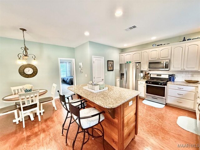 828 Warrior Dr, Valley Grande, AL 36701 - kitchen featuring stainless steel appliances, light wood-style floors, a kitchen island, light stone countertops, and decorative light fixtures