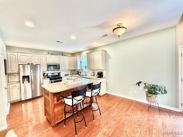 828 Warrior Dr, Valley Grande, AL 36701 - kitchen with stainless steel appliances, a kitchen breakfast bar, light wood-type flooring, tasteful backsplash, and a sink