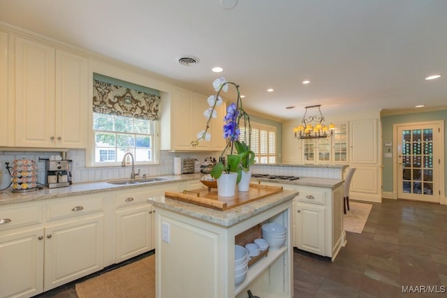 3410 Boxwood Dr, Montgomery, AL 36111 - kitchen with a sink, a kitchen island, decorative backsplash, white cabinets, and ornamental molding