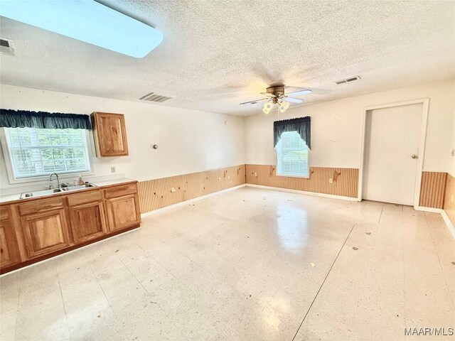 441 County Road 401, Selma, AL 36701 - kitchen featuring a sink, wainscoting, a textured ceiling, brown cabinets, and healthy amount of natural light