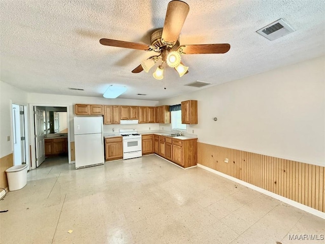 441 County Road 401, Selma, AL 36701 - kitchen featuring white appliances, under cabinet range hood, a sink, a textured ceiling, and a wainscoted wall