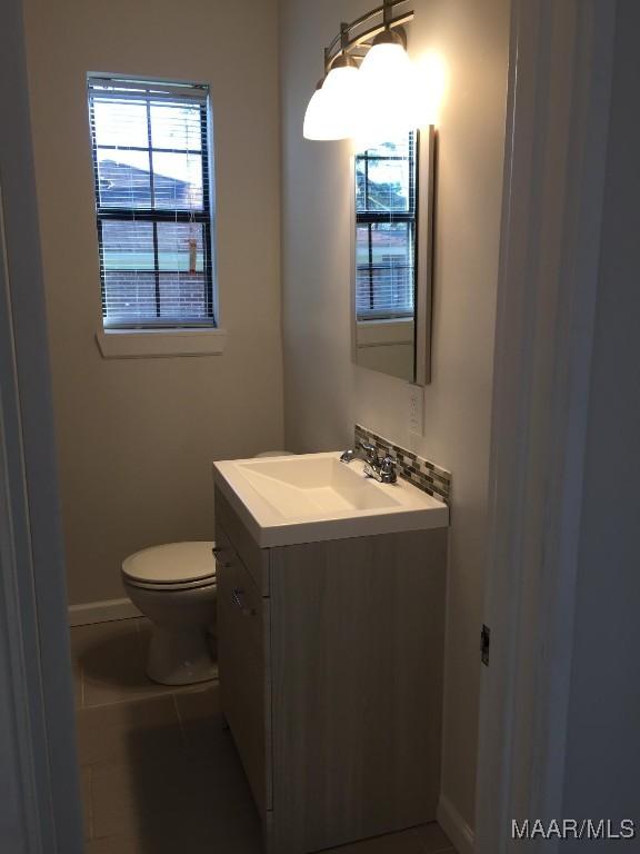 1324-1326 Federal Dr, Montgomery, AL 36107 - half bathroom featuring vanity, toilet, baseboards, and tile patterned flooring