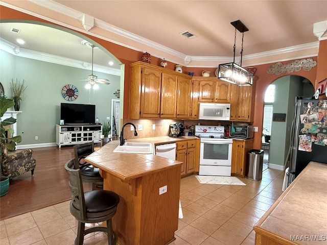 40 Larkspur Ln, Millbrook, AL 36054 - kitchen with white appliances, a sink, arched walkways, light tile patterned floors, and a peninsula