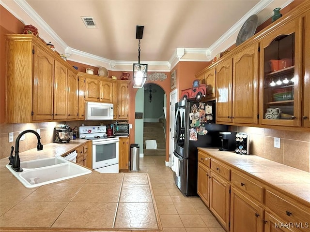 40 Larkspur Ln, Millbrook, AL 36054 - kitchen featuring white appliances, a sink, tile countertops, arched walkways, and light tile patterned floors