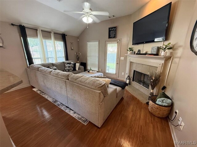 3701 Claiborne Cir, Montgomery, AL 36116 - living room featuring wood finished floors, a ceiling fan, baseboards, a tiled fireplace, and vaulted ceiling