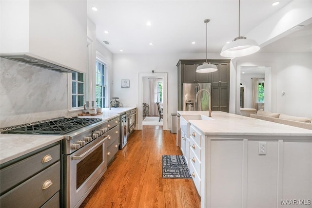 3328 Lebron Rd, Montgomery, AL 36106 - kitchen with high end stove, custom exhaust hood, a sink, light wood-style flooring, and an island with sink