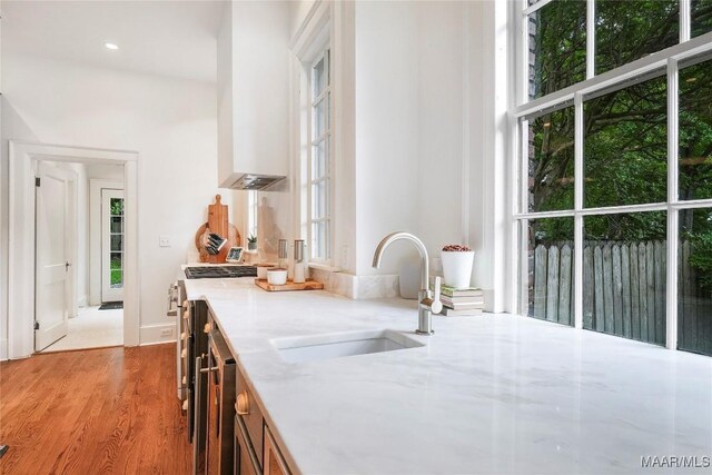 3328 Lebron Rd, Montgomery, AL 36106 - kitchen featuring a sink, light stone counters, light wood-style floors, wall chimney exhaust hood, and beverage cooler
