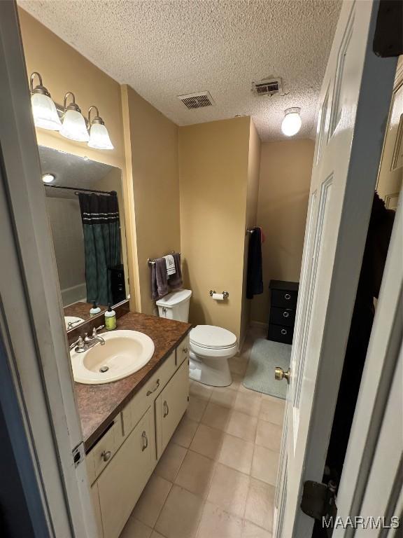 215 W Castlewood Dr, Selma, AL 36701 - full bathroom with vanity, toilet, a textured ceiling, tile patterned floors, and a shower with shower curtain