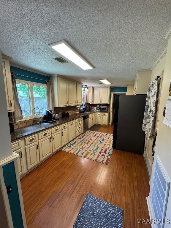 215 W Castlewood Dr, Selma, AL 36701 - kitchen featuring freestanding refrigerator, a textured ceiling, stainless steel dishwasher, light wood-type flooring, and dark countertops