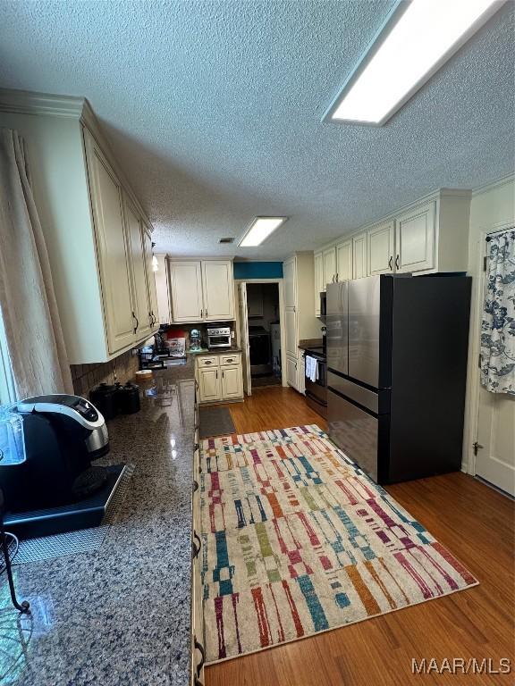 215 W Castlewood Dr, Selma, AL 36701 - kitchen featuring freestanding refrigerator, a textured ceiling, dark countertops, ornamental molding, and black / electric stove