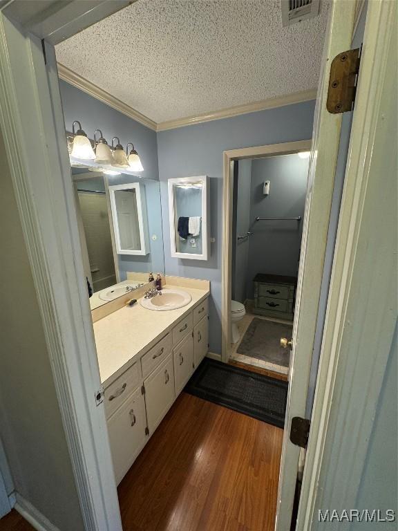 215 W Castlewood Dr, Selma, AL 36701 - bathroom with ornamental molding, a textured ceiling, wood finished floors, toilet, and vanity