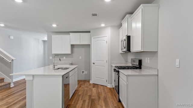6008 Cunningham Trl, Montgomery, AL 36116 - kitchen with stainless steel appliances, wood finished floors, recessed lighting, a kitchen island with sink, and white cabinetry