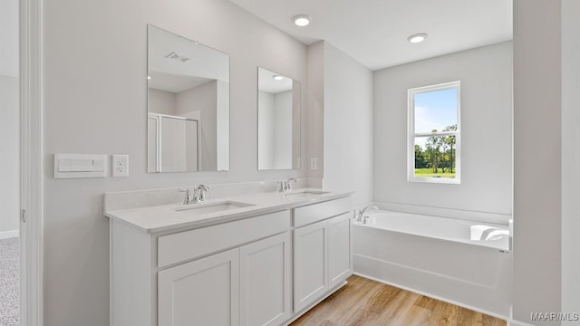 6008 Cunningham Trl, Montgomery, AL 36116 - bathroom featuring double vanity, a garden tub, a shower with door, and wood finished floors