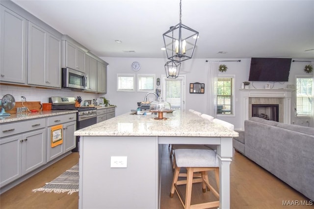 688 Tiger Trl, Opelika, AL 36804 - kitchen featuring appliances with stainless steel finishes, gray cabinetry, a kitchen bar, open floor plan, and light wood-type flooring