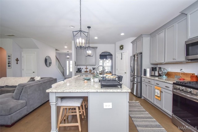 688 Tiger Trl, Opelika, AL 36804 - kitchen featuring appliances with stainless steel finishes, gray cabinetry, arched walkways, open floor plan, and a breakfast bar area
