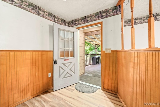 6390 County Road 37, Valley Grande, AL 36701 - doorway to outside with wainscoting, light wood-type flooring, wooden walls, and a textured ceiling