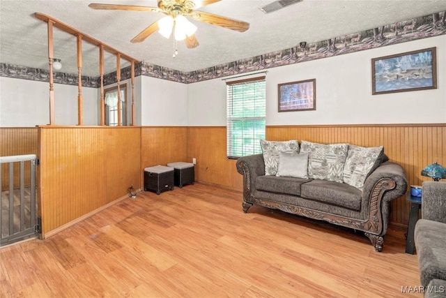 6390 County Road 37, Valley Grande, AL 36701 - living room featuring wainscoting, wood finished floors, ceiling fan, wood walls, and a textured ceiling
