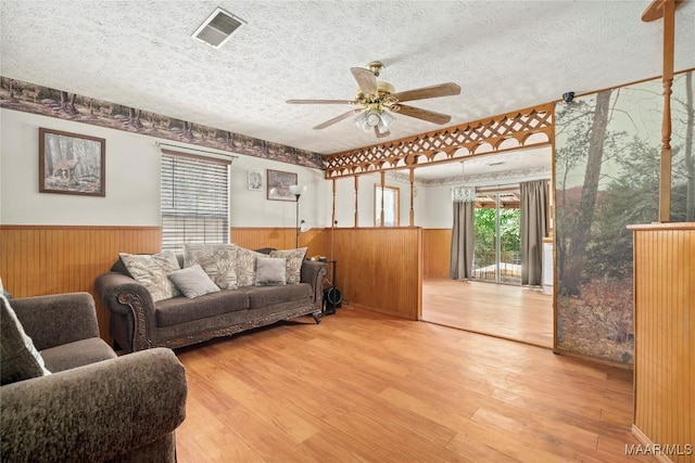 6390 County Road 37, Valley Grande, AL 36701 - living room featuring a wainscoted wall, a textured ceiling, a ceiling fan, wood finished floors, and wood walls
