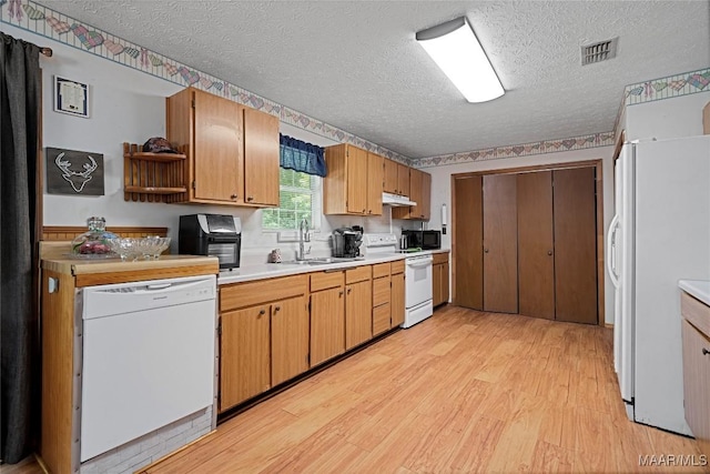 6390 County Road 37, Valley Grande, AL 36701 - kitchen with white appliances, light wood-style floors, a sink, a textured ceiling, and under cabinet range hood