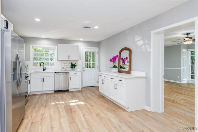 3212 Mcgehee Rd, Montgomery, AL 36111 - kitchen featuring appliances with stainless steel finishes, light wood finished floors, decorative backsplash, white cabinets, and light countertops