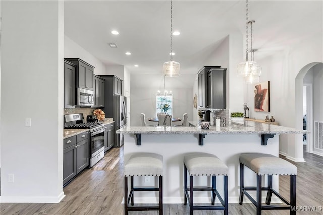 400 Lismore Pl, Montgomery, AL 36117 - kitchen featuring appliances with stainless steel finishes, a chandelier, arched walkways, a breakfast bar, and backsplash