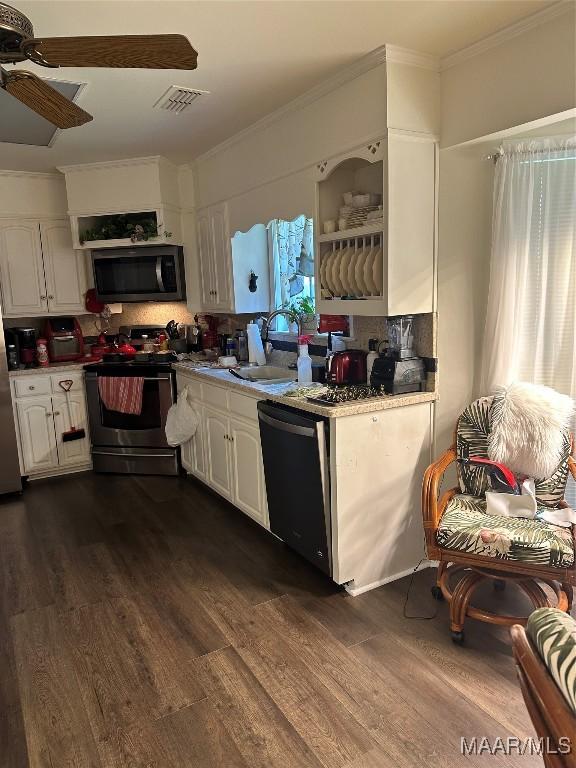 3932 Oak Ave, Montgomery, AL 36109 - kitchen featuring appliances with stainless steel finishes, dark wood finished floors, white cabinets, ceiling fan, and ornamental molding