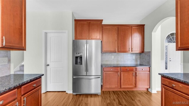 8 Honor Dr, Fort Mitchell, AL 36856 - kitchen with stainless steel refrigerator with ice dispenser, light wood-style floors, decorative backsplash, arched walkways, and dark stone counters