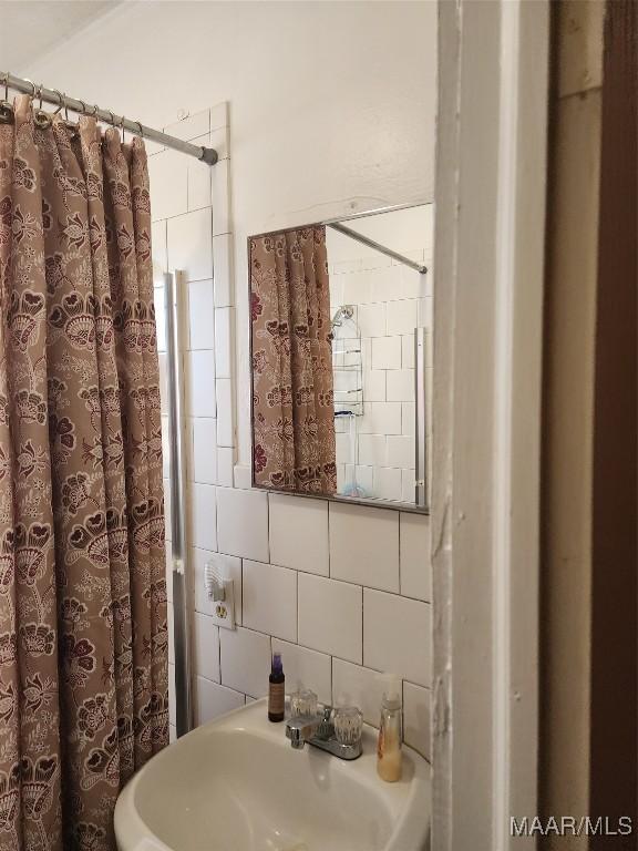 2110 Luverne St, Montgomery, AL 36104 - bathroom featuring a shower with shower curtain, decorative backsplash, and a sink