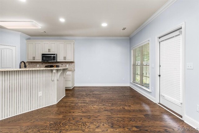 9148 Autumnbrooke Way, Montgomery, AL 36117 - kitchen featuring stainless steel microwave, backsplash, ornamental molding, light stone countertops, and dark wood-style flooring