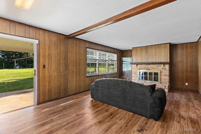 5241 County Road 48th Rd, Jemison, AL 35085 - living room featuring wood finished floors, wooden walls, a textured ceiling, beam ceiling, and a brick fireplace