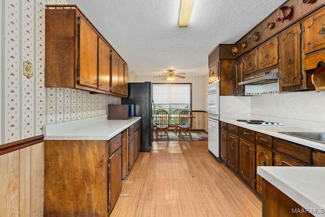 5241 County Road 48th Rd, Jemison, AL 35085 - kitchen with wallpapered walls, under cabinet range hood, light wood-style flooring, a textured ceiling, and ceiling fan