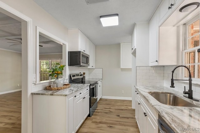 302 Janice St, Prattville, AL 36066 - kitchen featuring appliances with stainless steel finishes, a sink, light wood-type flooring, and light stone counters